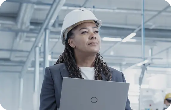 an image of a woman at a factory, she is wearing a suit and a hard hat